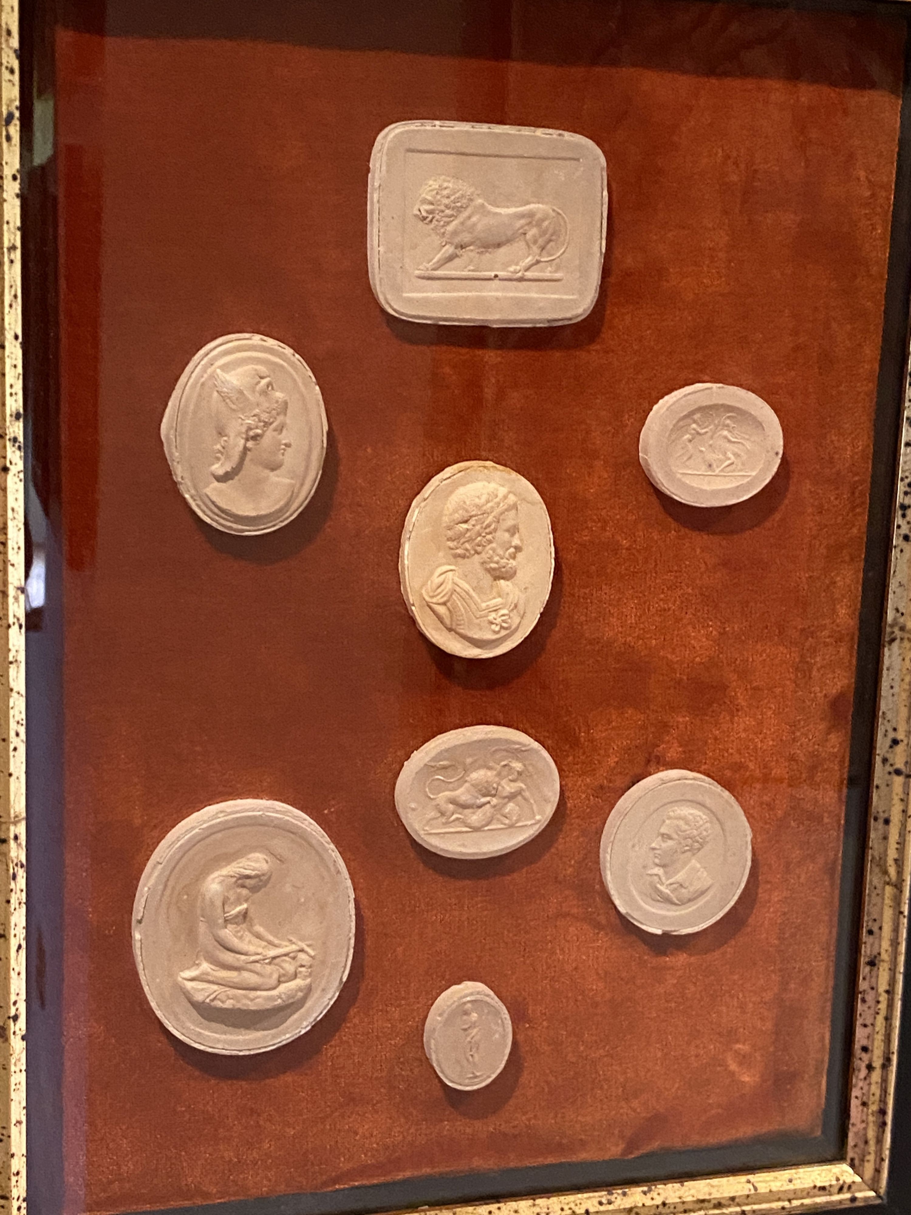 A collection of thirty four framed reproduction plaster intaglios, on velvet backing with parcel gilt ebonised frames, overall 45 x 35cm